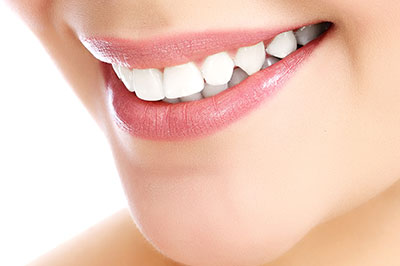 A close-up photo of a smiling woman showcasing her teeth, with an emphasis on the dental product she s using.