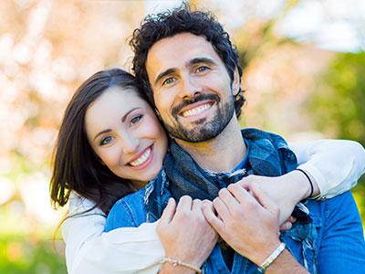 A man and a woman are smiling at the camera, posing for a portrait.