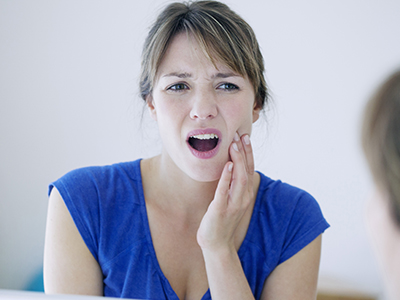 Woman with hand on face, expressing concern or surprise.